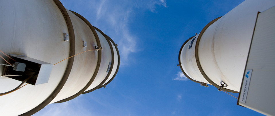 Two Hofstetter gas flare stacks against a blue sky