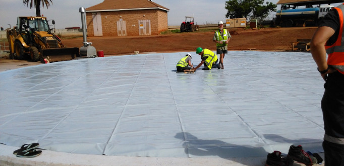 Sattler double-membrane gas holder foundation and membrane being laid out at Welgedacht